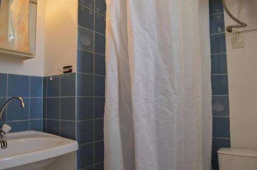 La salle de bains est pourvue d'un rideau de douche blanc et d'un lavabo. dans l'établissement SP280-124 Appt Studio Cabine 4 couchages SAINT PIERRE LA MER, à Saint Pierre La Mer