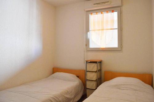 deux lits dans une chambre avec une fenêtre dans l'établissement NP100-2203 Appartement 3 pièces, Narbonne Plage, à Narbonne-Plage