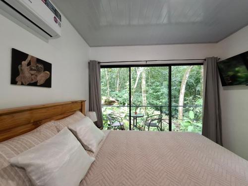 a bedroom with a bed and a large window at Forest Love in Quepos