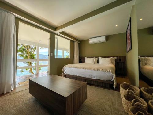 a bedroom with a bed and a table and a window at Pousada Papiro Boutique in Abraão
