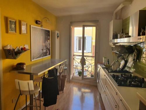 eine Küche mit gelben Wänden, einem Tisch und einer Theke in der Unterkunft A casa di Giò e Lorenzo- Appartamento via Guidelli in Reggio nell'Emilia