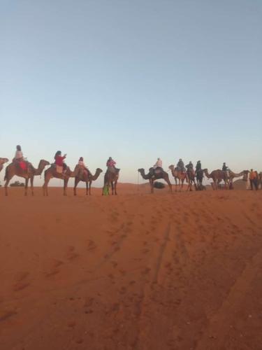 a group of people riding horses in the desert at merzouga desert camp in Merzouga