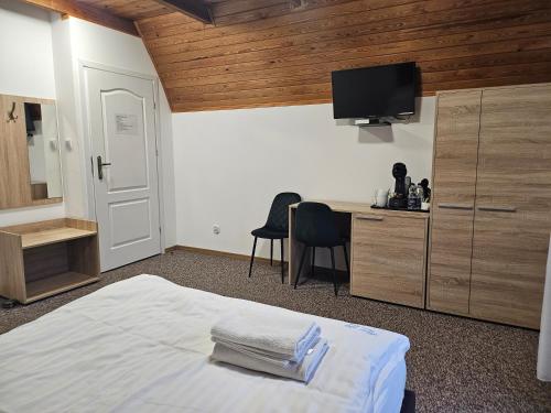 a bedroom with a bed and a desk with a television at "Hel" Wieniec Zdrój in Włocławek