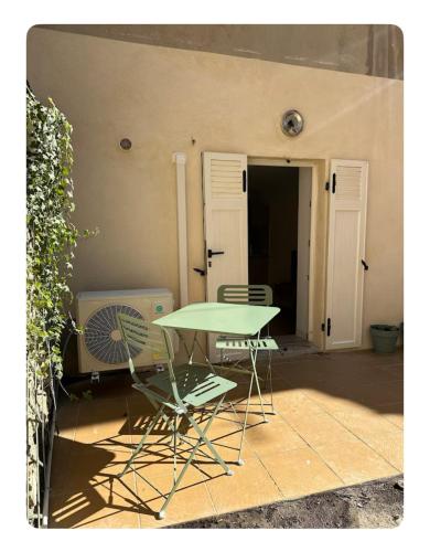 une table verte et deux chaises à côté d'un bâtiment dans l'établissement Le Camas Cosy - Rez de Jardin, à Marseille