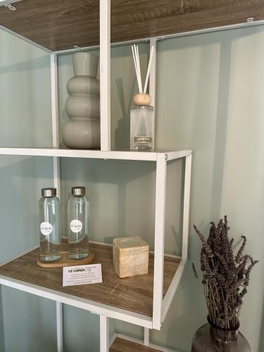 une étagère blanche avec des bouteilles en verre et une boîte dans l'établissement Le Camas Cosy - Rez de Jardin, à Marseille