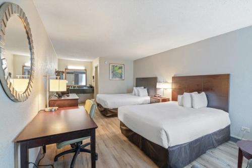 a hotel room with two beds and a desk and a mirror at Plantation Inn in Houma
