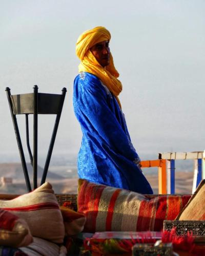 a woman in a blue robe standing next to a chair at La Dune Agafay Desert Camp in Marrakech