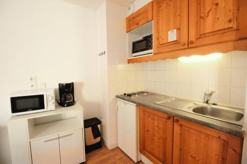 une petite cuisine avec un évier et un micro-ondes dans l'établissement Chalets De La Vanoise - CHALETS DE LA VANOISE - CV5205 MAE-4614, à Villarodin-Bourget