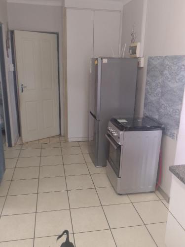 a kitchen with a refrigerator and a black cat on the floor at eagles inn in Richards Bay