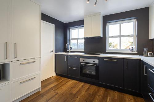 a kitchen with black and white cabinets and wood floors at Host & Stay - Martinhoe in Yarm