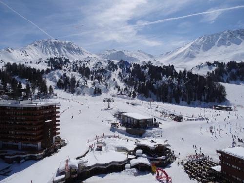 une piste de ski couverte de neige avec un lodge et des montagnes dans l'établissement Superbe appt ensoleillé au cœur de Plagne Centre, à La Plagne Tarentaise