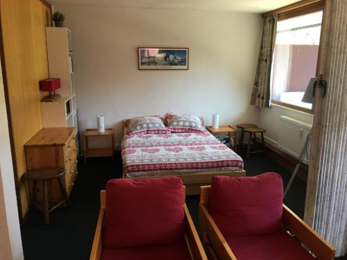 - une chambre avec un lit et deux chaises rouges dans l'établissement Superbe appt ensoleillé au cœur de Plagne Centre, à La Plagne Tarentaise