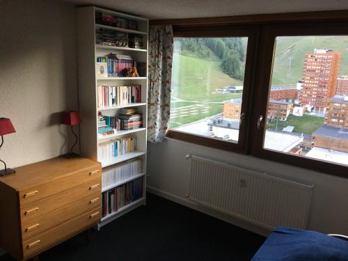 - une chambre avec une fenêtre et une étagère avec des livres dans l'établissement Superbe appt ensoleillé au cœur de Plagne Centre, à La Plagne Tarentaise