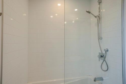 a white bathroom with a shower and a tub at Le Studio Cohen "parking inclus" in Quebec City