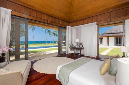a bedroom with a bed and a view of the ocean at Villa Sundara - SHA Extra Plus in Natai Beach