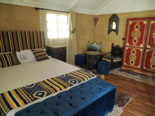 a bedroom with a large bed and a blue couch at La Dune Agafay Desert Camp in Marrakech