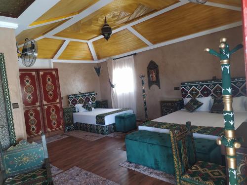 a bedroom with two beds and a wooden ceiling at La Dune Agafay Desert Camp in Marrakech
