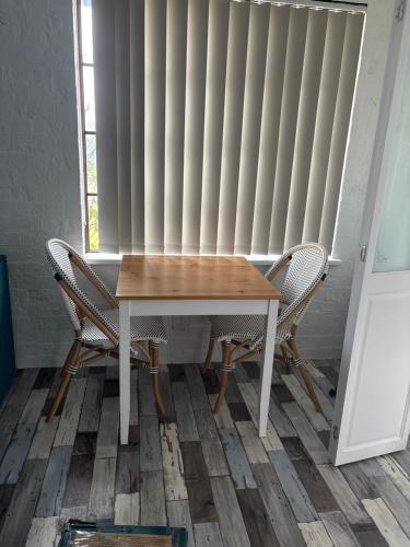a wooden table with two chairs in front of a radiator at Beach N Berms in Dalmeny