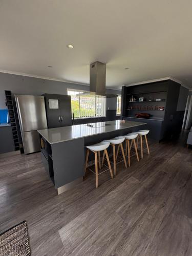 a kitchen with a large counter and stools in it at Beach N Berms in Dalmeny