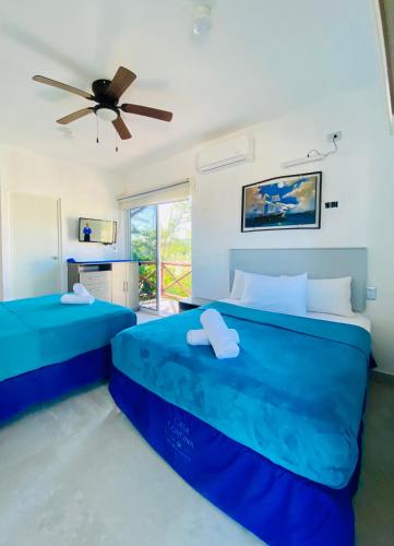 two beds in a room with a ceiling fan at Casa Coronaa Holbox México in Holbox Island