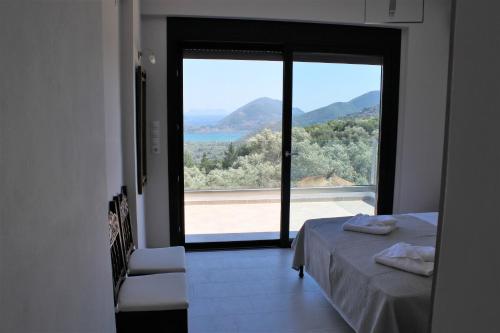 a bedroom with a large window with a view of the ocean at Villa Maura-Lefkada - Jimdo in Nydri