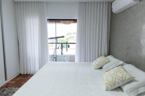 een slaapkamer met een groot wit bed met twee kussens bij Casa Enorme com Piscina, Sauna e Área para Festas in Belo Horizonte