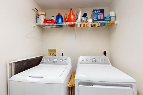 a laundry room with two white washing machines and a shelf at Oceanwalk 1-1405 in New Smyrna Beach