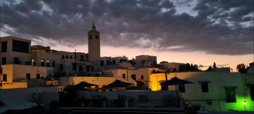 a group of buildings with a clock tower in the background at Dar Ben Jemia- Sidi Bou Saïd in Sidi Bou Saïd