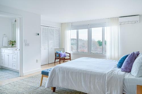a white bedroom with a large bed and a chair at Field of Dreams in Truro