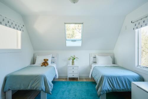 two beds in a white room with a teddy bear sitting between them at Field of Dreams in Truro