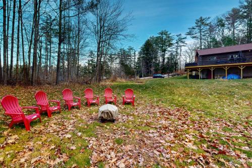 a group of red chairs sitting in a field at Loon Lodge on Locke Lake in Center Barnstead