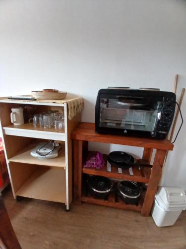 a microwave oven sitting on a stand next to a shelf at DEPARTAMENTO RINCON DE MINA in Mar del Plata