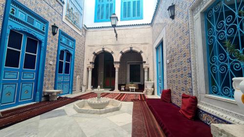 a courtyard with a fountain in a building with blue doors at Dar Ben Jemia- Sidi Bou Saïd in Sidi Bou Saïd