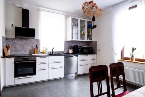 a kitchen with white cabinets and two chairs in it at Obere Stadtwohnung in Michelstadt