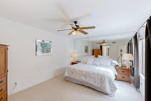 une chambre blanche avec un lit et un ventilateur de plafond dans l'établissement Solstice Sanctuary, à Tucson
