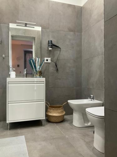 een badkamer met een wastafel, een toilet en een spiegel bij Alle porte del Castello 23 in Catania