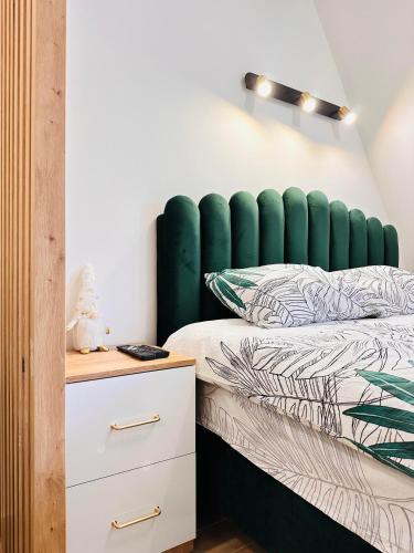 a bed with a green headboard in a bedroom at Lexi Green Hills apartman in Divčibare