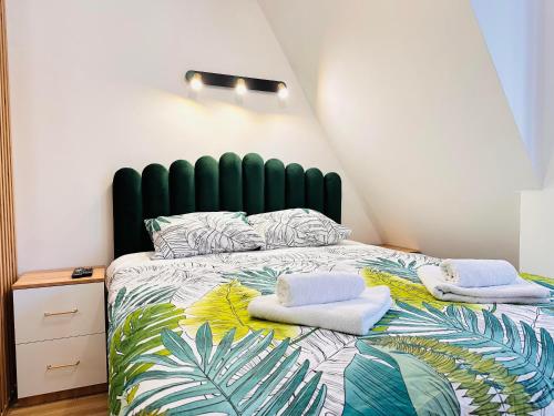 a bedroom with a large bed with towels on it at Lexi Green Hills apartman in Divčibare