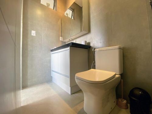 a bathroom with a toilet and a sink and a mirror at Prado Premium Lofts e Kitnets com Ar-Condicionado e TV Smart in Belo Horizonte