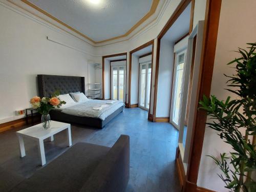 a bedroom with a bed and a table and some windows at Parque Eduardo VII in Lisbon
