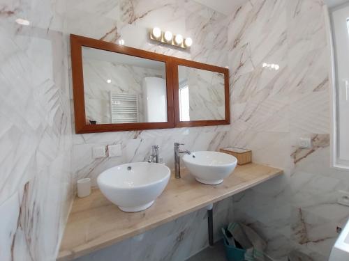 une salle de bain avec deux lavabos blancs et un miroir dans l'établissement Maison Les Blés d'Or, plain-pied, Wi-Fi, parking privé, à Hem-Lenglet