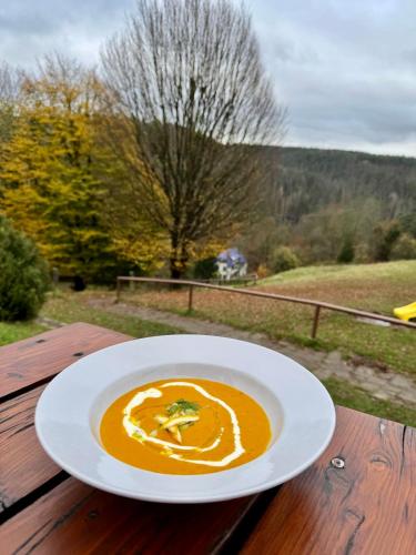 a plate of soup sitting on a wooden table at Resort Mezná in Hřensko