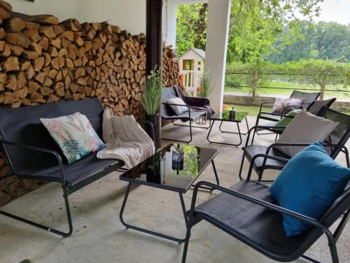 a patio with chairs and a wall of logs at Bárka a Tiszához apartman in Tiszaug