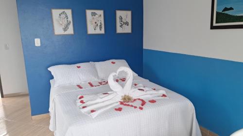 a bed with a white blanket with a flower on it at Suítes Encanto do Pai in Praia de Araçatiba