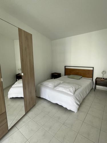 - une chambre avec un grand lit blanc et 2 tables dans l'établissement Le soleil Niçois, proche du port, à Nice