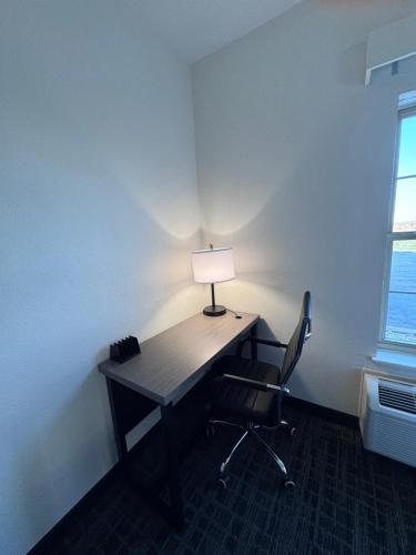 a desk with a lamp and a chair in a room at Ramada by Wyndham Sparta/At Speedway in Sparta