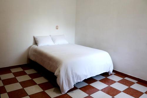 a white bed in a room with a checkered floor at Departamento Bugambilia in Oaxaca City