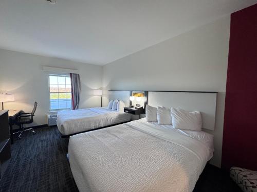 a hotel room with two beds and a desk at Ramada by Wyndham Sparta/At Speedway in Sparta