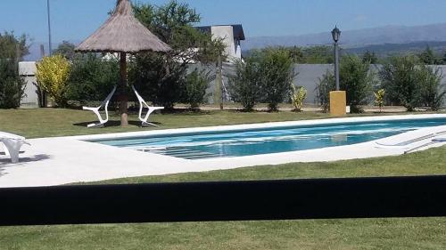 a swimming pool with two chairs and an umbrella at Melodias Posada Boutique in Los Reartes