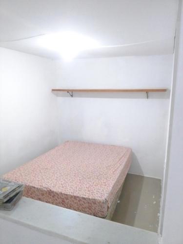 um pequeno quarto com uma cama e uma prateleira em Kitnet na praia da Macumba no morro do Rangel no Rio de Janeiro